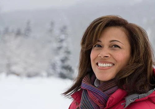 Woman smiling outdoors in cold winter air, a common trigger for sensitive teeth