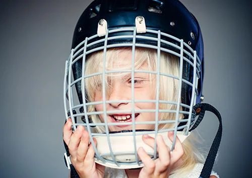 Young athlete holding a sports helmet with a face cage over a big smile