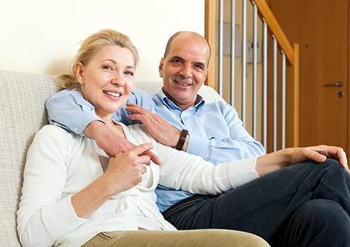 Older couple relaxing at home, the age group where gum recession becomes more common