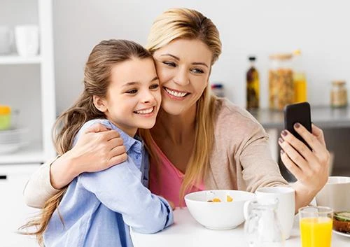 Young adult at a kitchen table holding one hand to the jaw in discomfort
